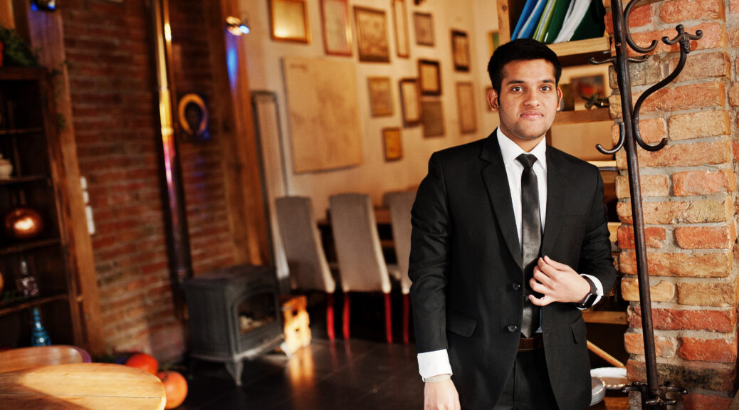 Elegant south asian indian business man in black suit posed indoor cafe.