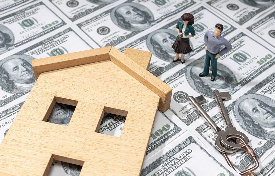 Investing in a house concept. Real estate prices. Toy house and figurine couple on dollar banknote background